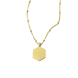 Al-Qadīr Necklace in gold featuring Arabic Quran verse “Wa Huwa ‘Alā Kulli Shay’in Qadīr” engraved on a geometric hexagon pendant, displayed on a white background.