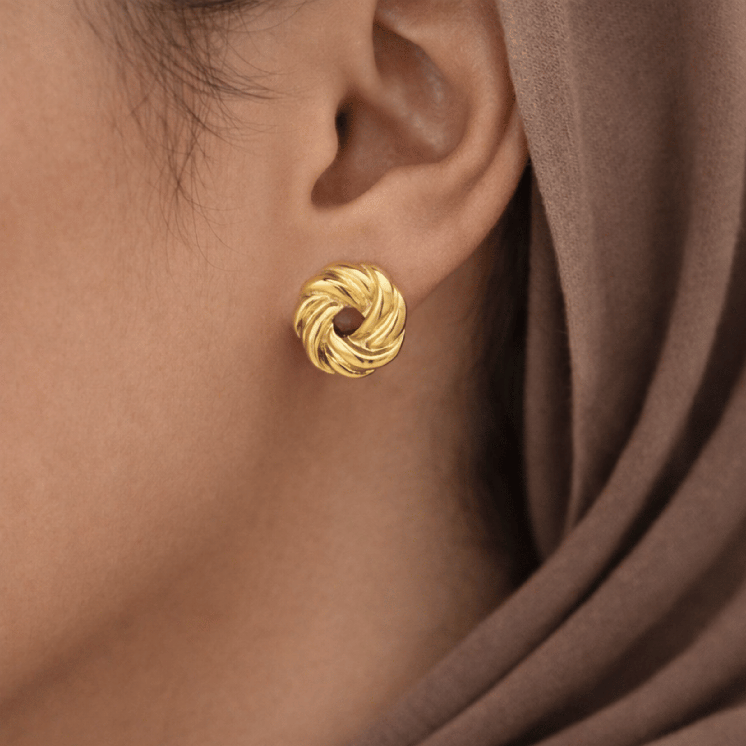Model wearing Aurelia Weave Studs in 18K gold plated stainless steel with woven knot design
