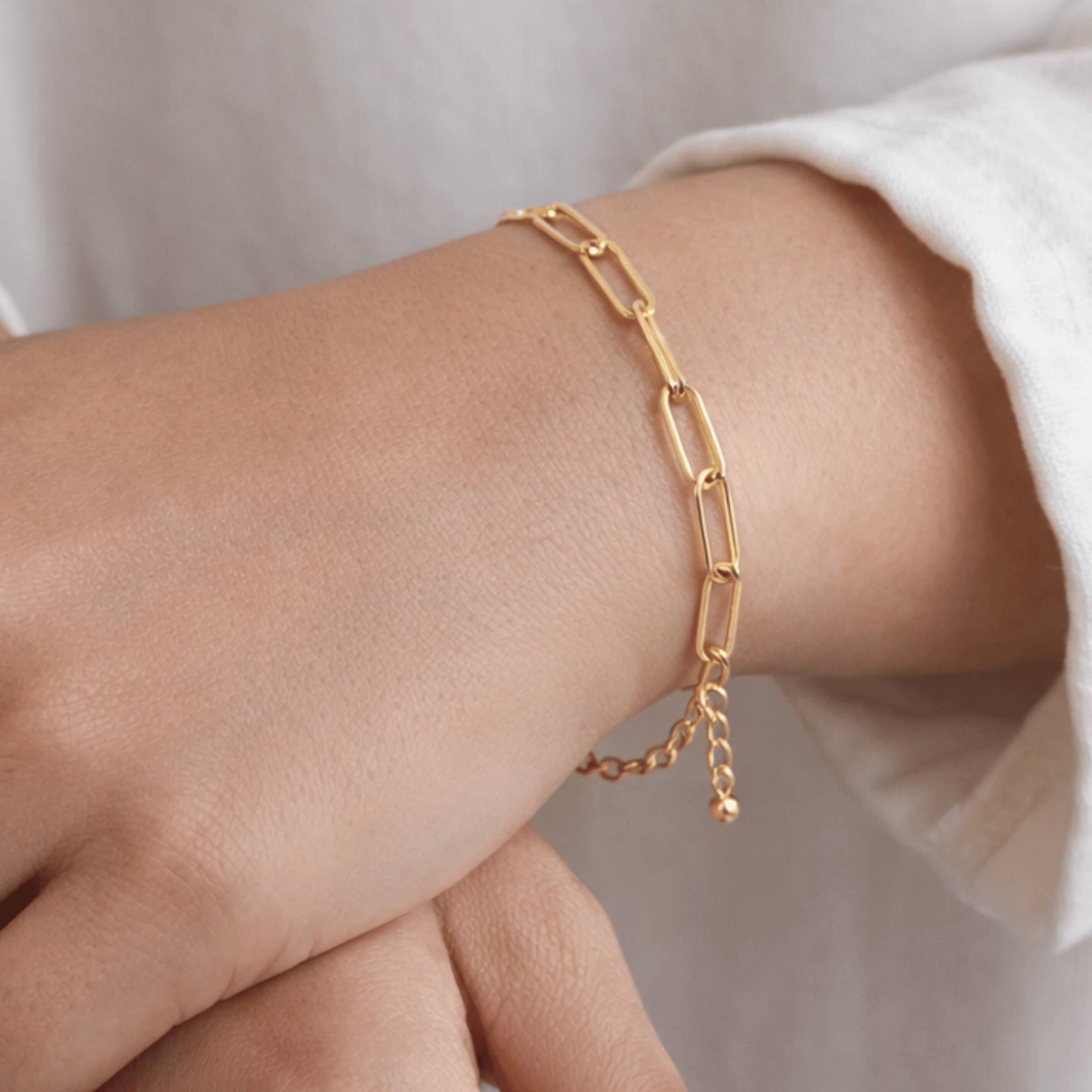Dainty Clip Bracelet worn on wrist featuring elongated gold paperclip-style links with adjustable extension chain