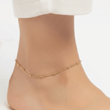 Dainty Dot Anklet worn on ankle featuring delicate gold bead accents and adjustable 8–10 inch fit