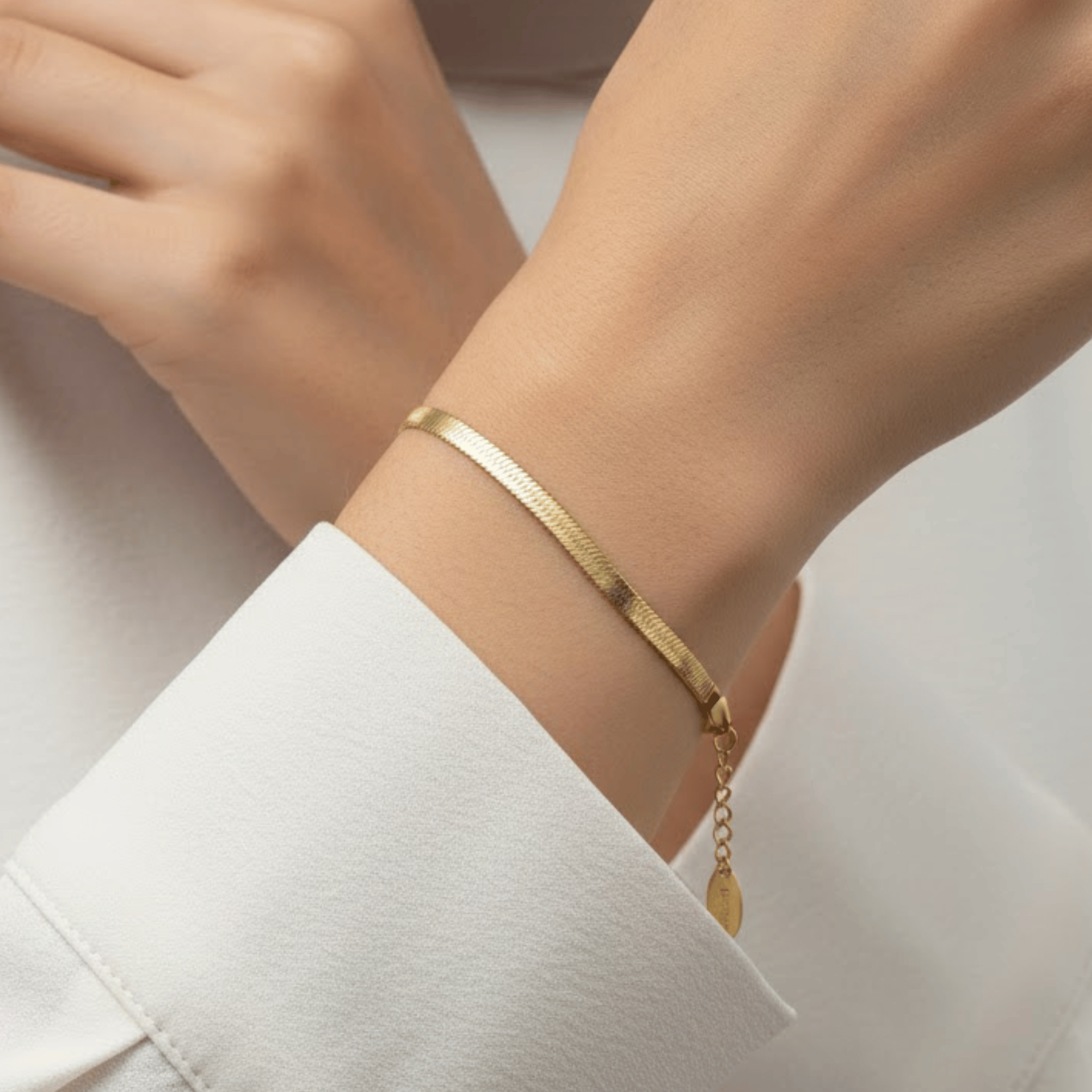Flat Herringbone Bracelet worn on wrist featuring wide polished 18K gold plated stainless steel chain