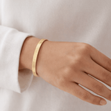 Side profile of gold Hidden Reminder Cuff highlighting slim silhouette and lightweight open cuff design.