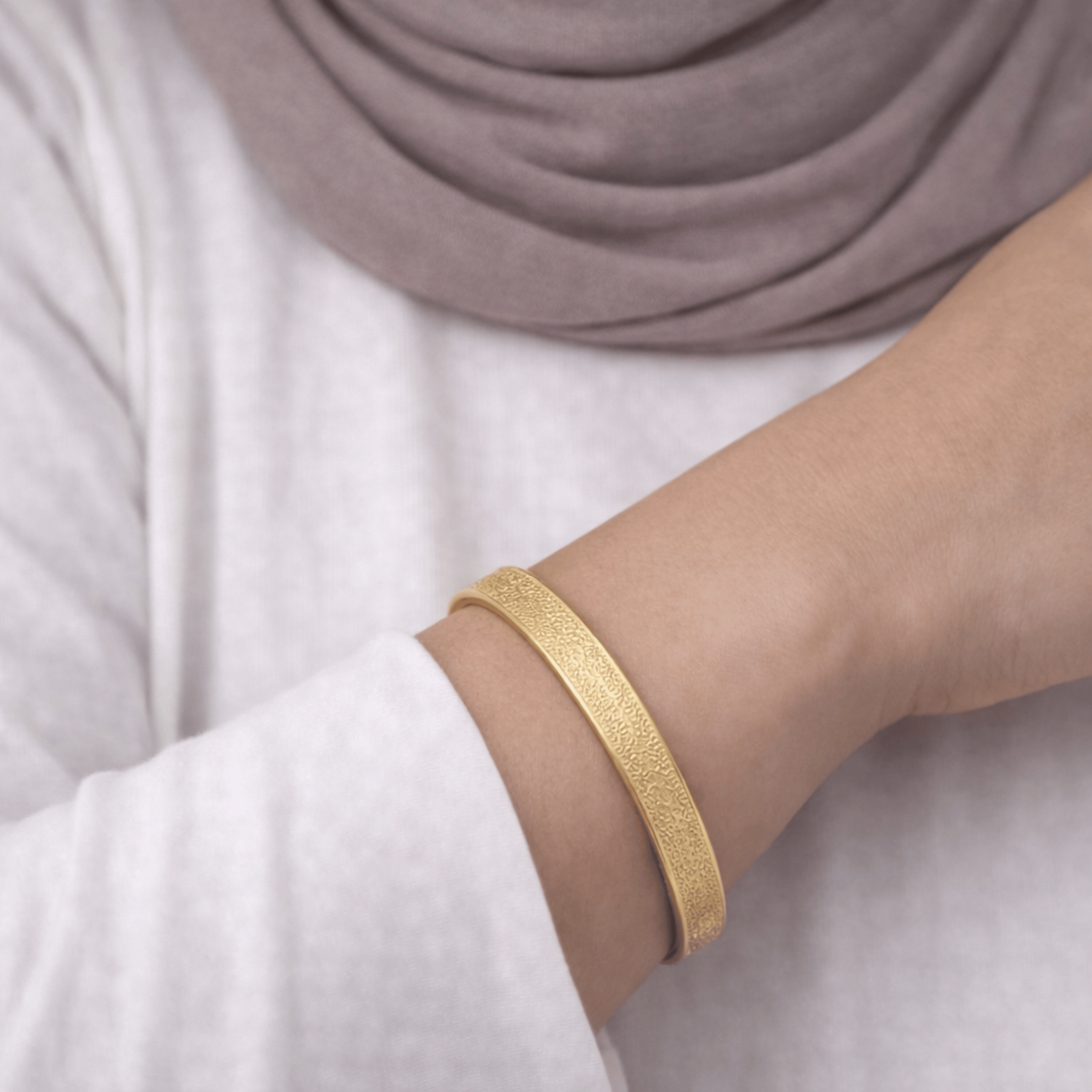 Close-up of gold Hidden Reminder Cuff showing intentionally subtle Arabic engraving of Sabr, Shukr, and Tawakkul.