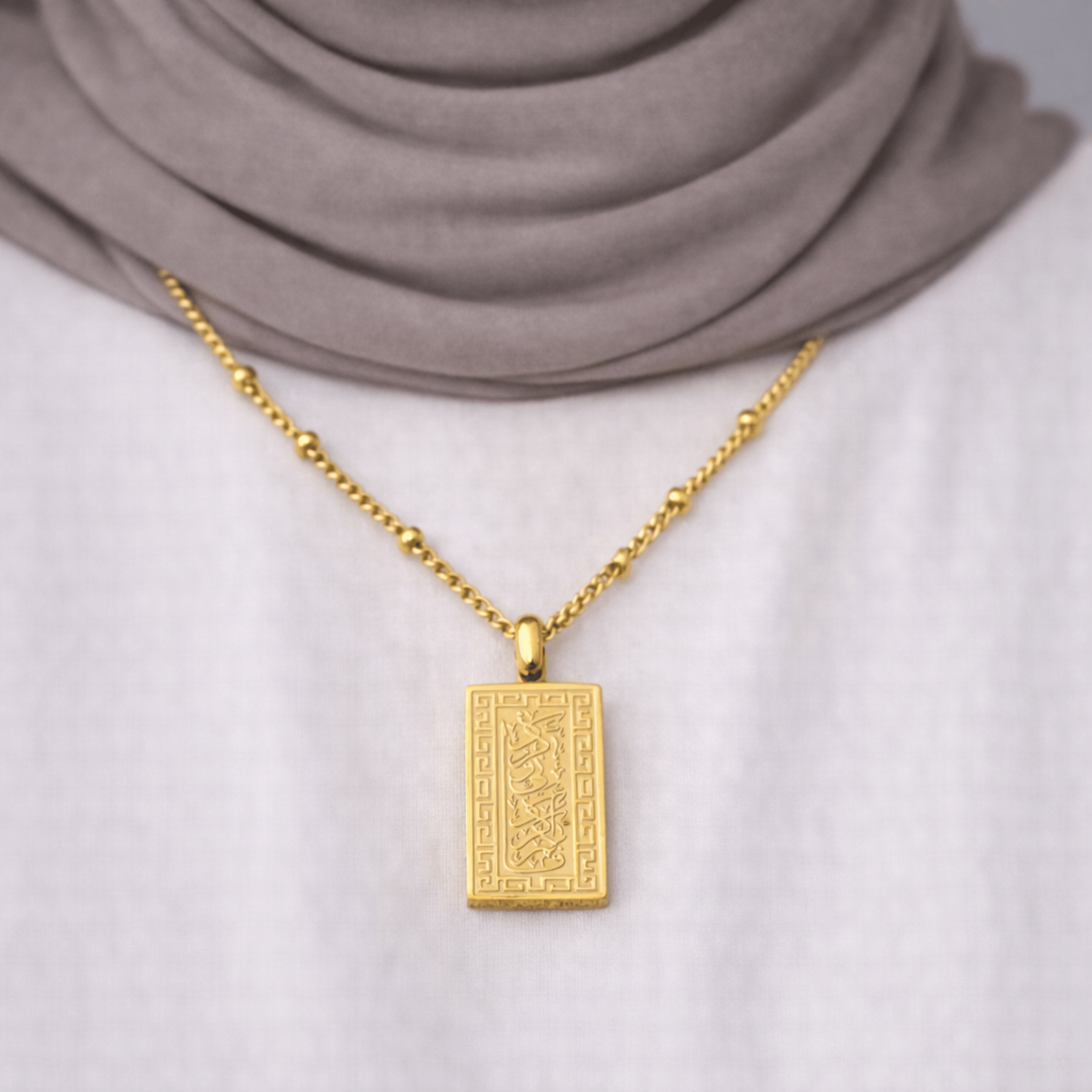 Gold Remember Me Necklace worn by a modest woman, featuring Quran verse from Surah Al-Baqarah Ayah 152, styled with a white top and neutral hijab.