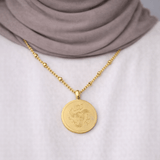 Gold Sabr, Shukr & Tawakkul Coin Necklace worn by a modest woman, featuring Arabic calligraphy for patience, gratitude, and trust in Allah, styled with a white top and neutral hijab.