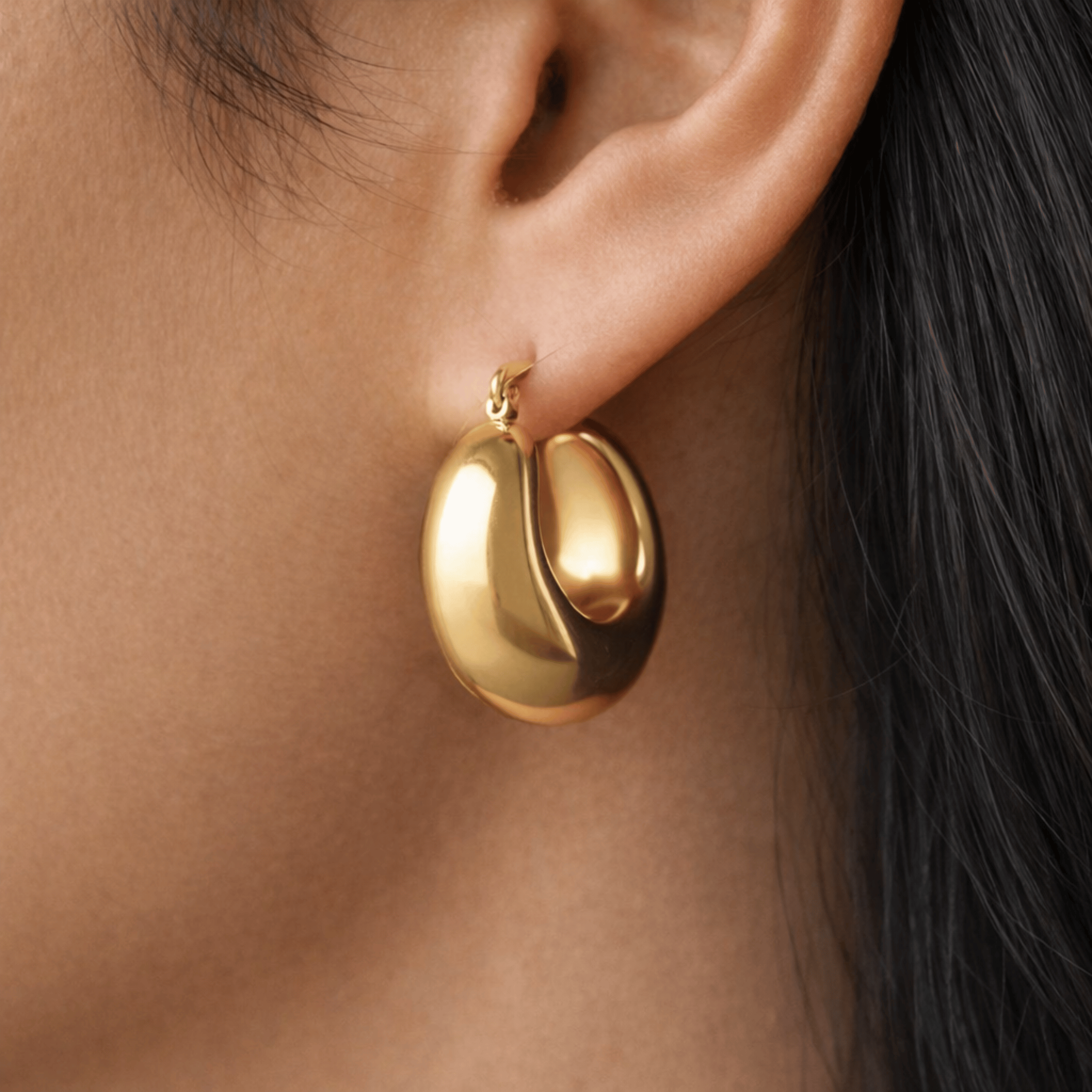 Model wearing Sculpted Gold Hoops in 18K gold plated stainless steel with smooth dome silhouette